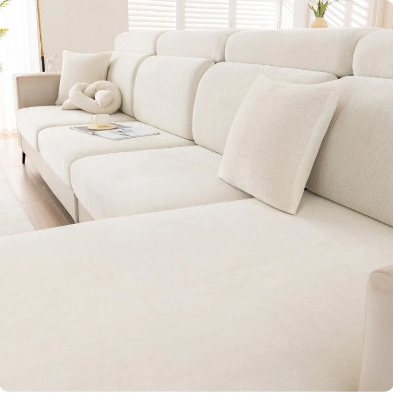 A cream-colored universal elastic sofa cover with a full backrest shown in a bright interior setting.
