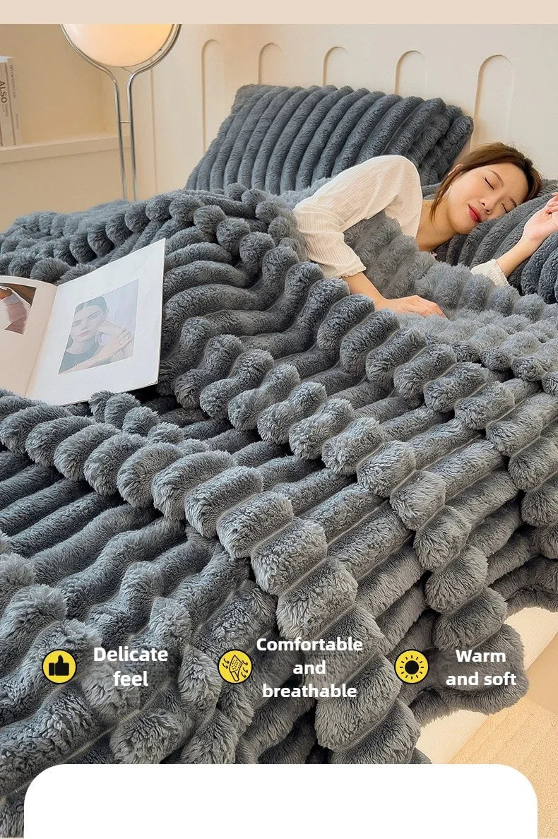 A woman relaxing under a thick gray faux fur blanket in bed.