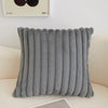 A gray, ribbed plush winter throw pillow cover resting on a light-colored sofa.