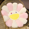 A cozy sunflower plush cushion with a smile face made of pink and white faux fur, displayed in a gold wire basket.