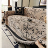 A beige chenille sofa slipcover with a black floral pattern is draped on a light-colored rug.