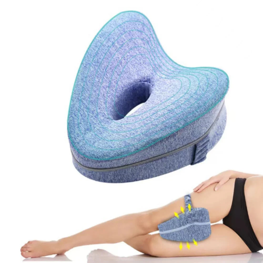 A blue memory foam heart leg pillow is shown resting on a person's leg for side sleeping or pregnancy support.