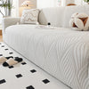 A white stretch sofa cover featuring a vertical ribbed pattern and decorative throw pillows.