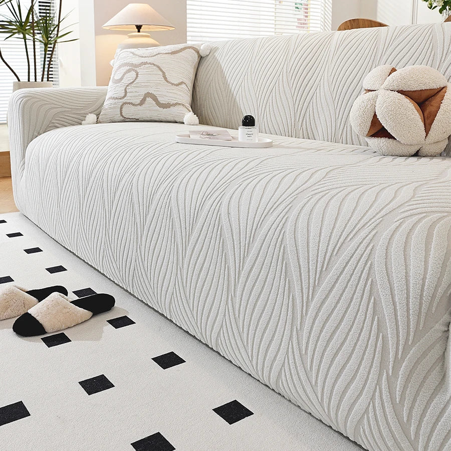 A white stretch sofa cover featuring a vertical ribbed pattern and decorative throw pillows.