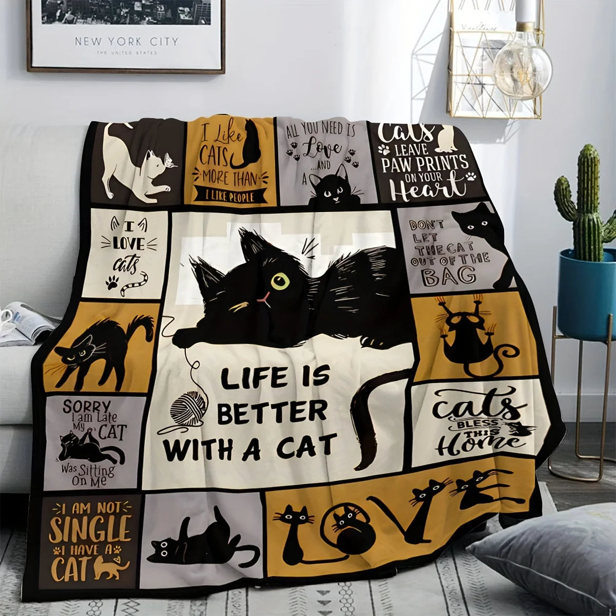 A black and gold patterned flannel throw blanket featuring various cat illustrations.