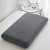 A gray ice silk cooling pillowcase lying on a white surface next to a small table with decorative items.