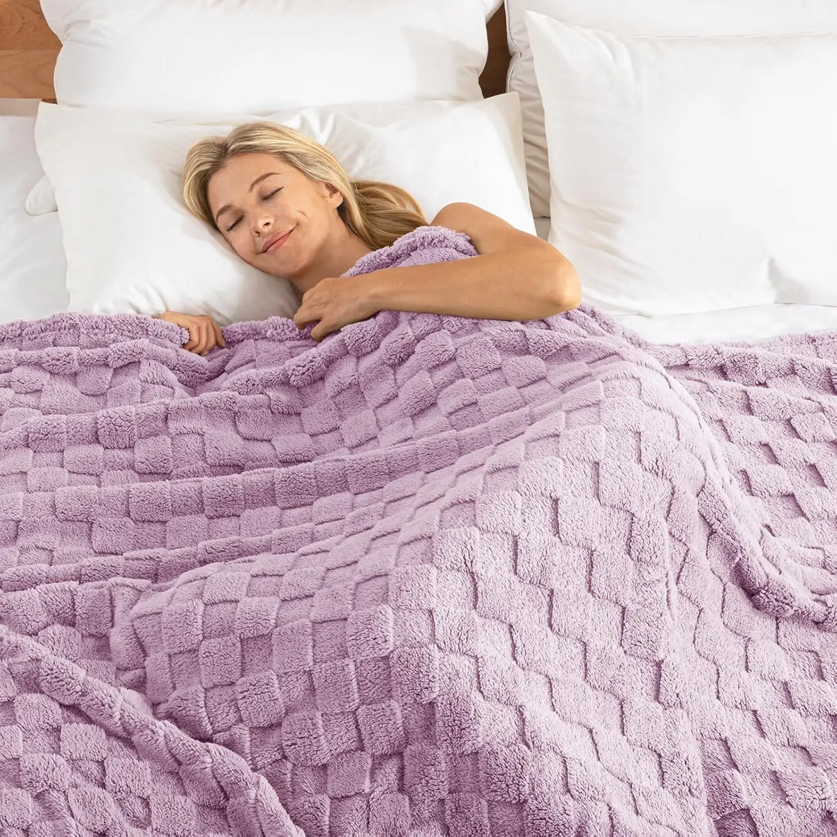 A woman rests her head on a white pillow while wrapped in a purple checkered fleece throw blanket.