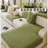 A light beige sofa covered with a green branch patterned jacquard fabric and matching cushions.