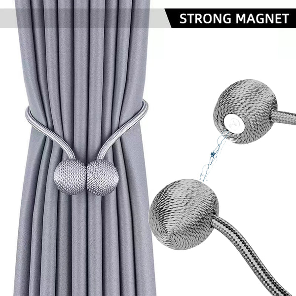 Close-up of a gray fabric curtain with magnetic ball tiebacks and a detachable cord.