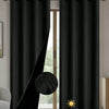 Solid black blackout window curtains hanging on a rod, showing the fabric texture and grommets.
