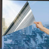 A hand holds a triangular piece of frosted insulated glass film against a cityscape view.