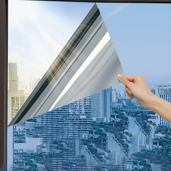 A hand holds a triangular piece of frosted insulated glass film against a cityscape view.