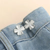 Silver clover-shaped button clips attached to a blue denim fabric