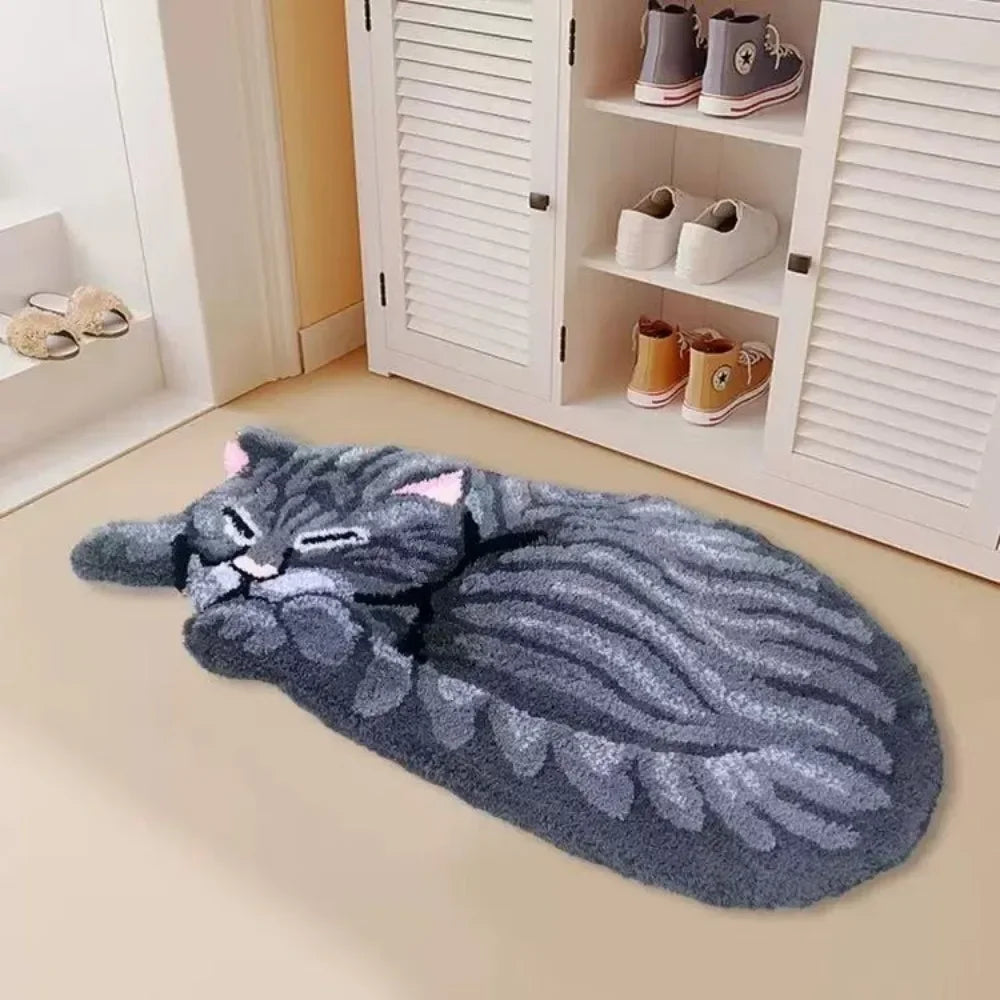 A gray cartoon cat plush rug lying on a light floor next to a white cabinet with shoes.