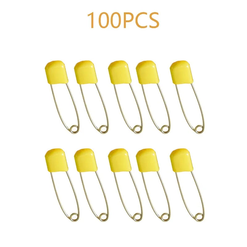 A collection of 100 yellow stainless steel diaper pins with safety locking closures.