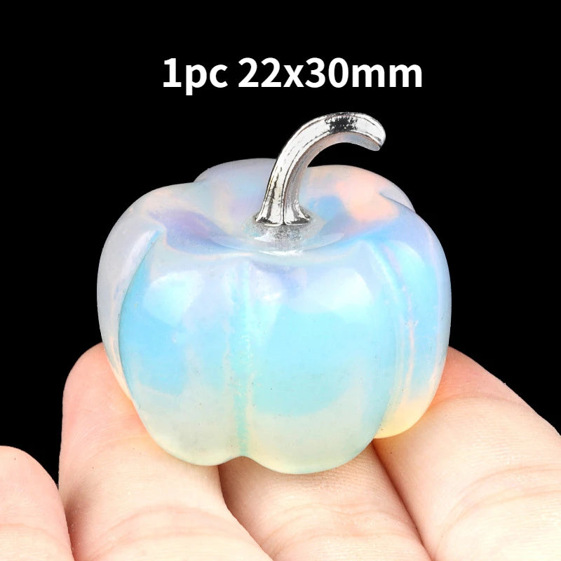 A translucent blue and white natural stone pumpkin figurine with a silver stem is held in a hand.
