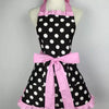 A pink and black polka dot ruffle apron with pockets displayed on a mannequin.