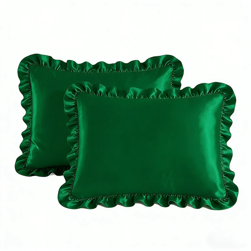 A set of two emerald green ruffled satin pillowcases with silky envelope closures.