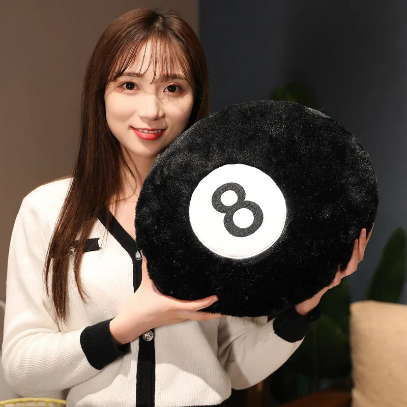 A woman holds a black 8 ball plush pillow with a white circle design.