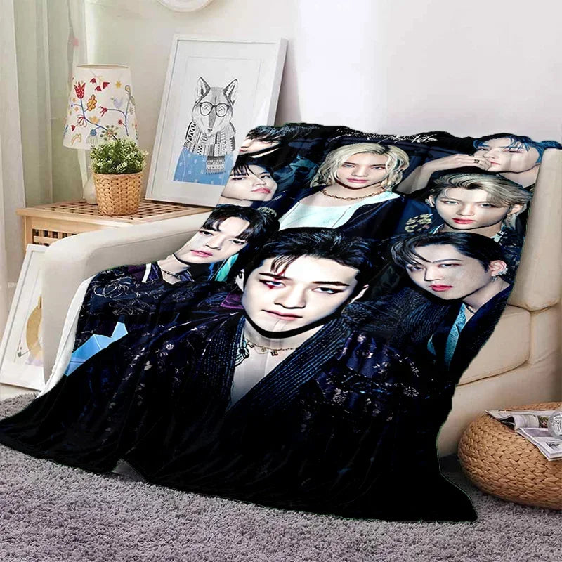 A black fleece throw blanket featuring multiple portraits of Stray Kids members printed on it.