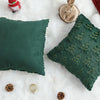 A dark green textured corduroy throw pillow cover resting on a white fluffy surface with small natural elements.
