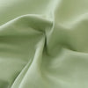 A close-up of a smooth, pale sage green polyester fabric pillow cover set.