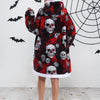 A woman wearing an oversized patchwork fleece hoodie with a skull print and bat design against a white wall.