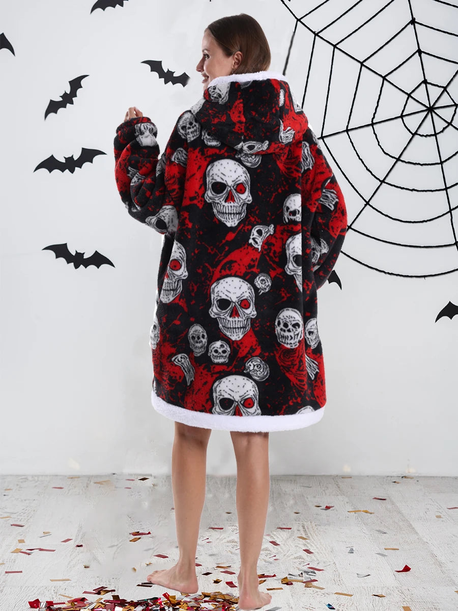 A woman wearing an oversized patchwork fleece hoodie with a skull print and bat design against a white wall.