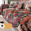 A richly colored romantic floral jacquard sofa throw blanket draped over a sofa with decorative pillows.