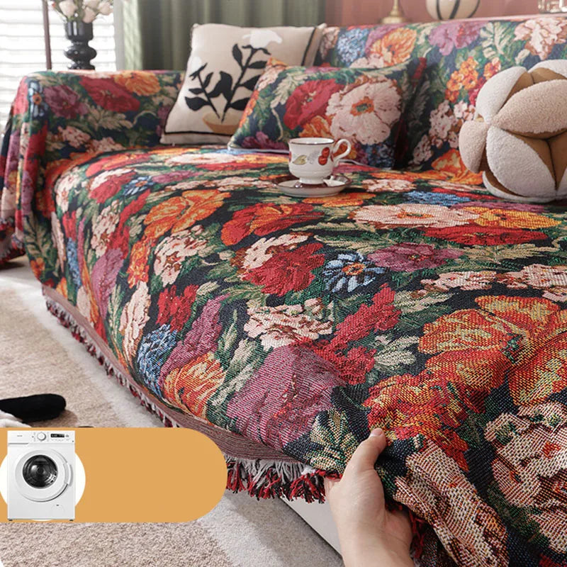 A richly colored romantic floral jacquard sofa throw blanket draped over a sofa with decorative pillows.
