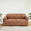 A modern, taupe-colored PU leather sofa slipcover placed in a bright living room setting.