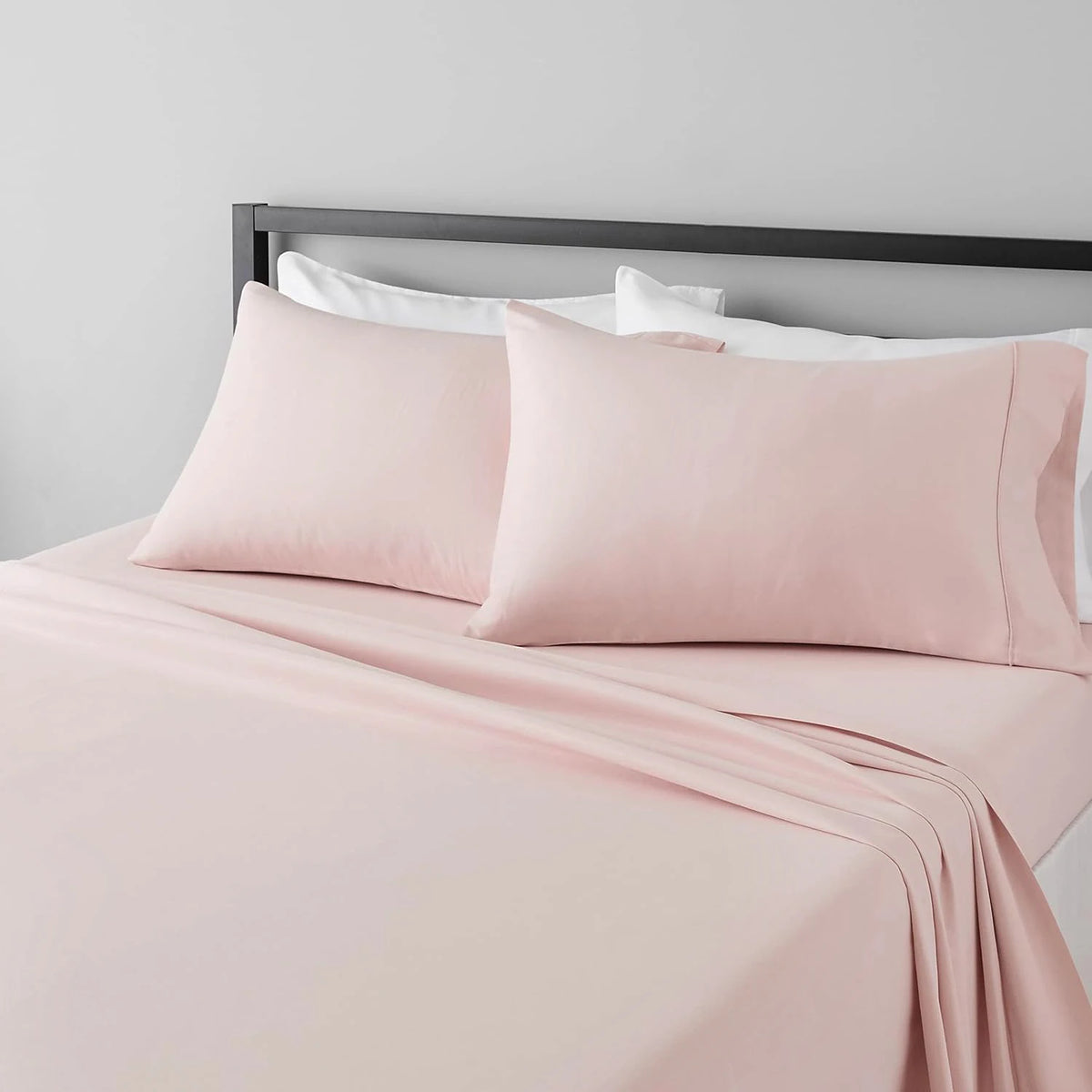 A pink microfiber flat fitted sheet set with pillows and a duvet on a bed.