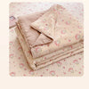 A stack of light pink cartoon quilting comforters with small pink and white floral patterns on a light pink quilted backgroun