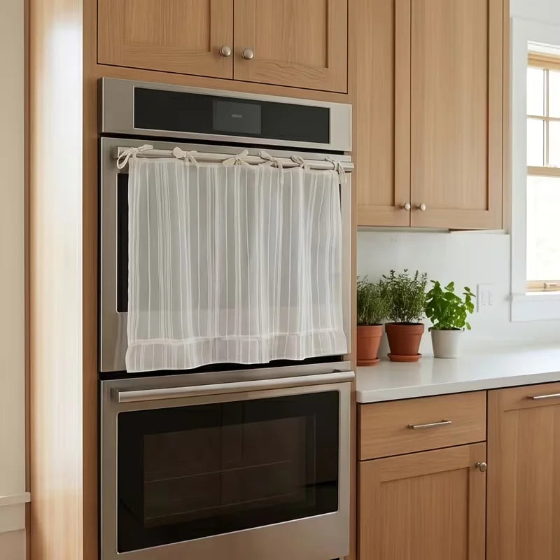 Stainless steel oven and microwave stacked within light wood cabinetry in a farmhouse kitchen