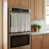 Stainless steel oven and microwave stacked within light wood cabinetry in a farmhouse kitchen