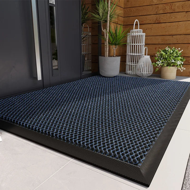 A dark blue non-slip rubber doormat with a diamond pattern placed on a light gray floor.