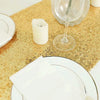 Golden sequin table runner with a white candle and a glass of wine on a gold textured surface.