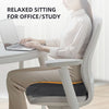 A woman is sitting in an office chair using an ergonomic U-shaped massage seat cushion for relaxed sitting.