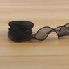 A roll of black satin ribbon used for DIY crafting, lying on a light wooden surface.