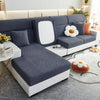 A modern gray sofa with a white slipcover featuring a large floral cushion and a rectangular mirror accent.