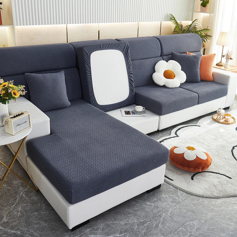 A modern gray sofa with a white slipcover featuring a large floral cushion and a rectangular mirror accent.