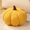 A bright yellow plush pumpkin throw pillow with a textured surface and a brown stem.