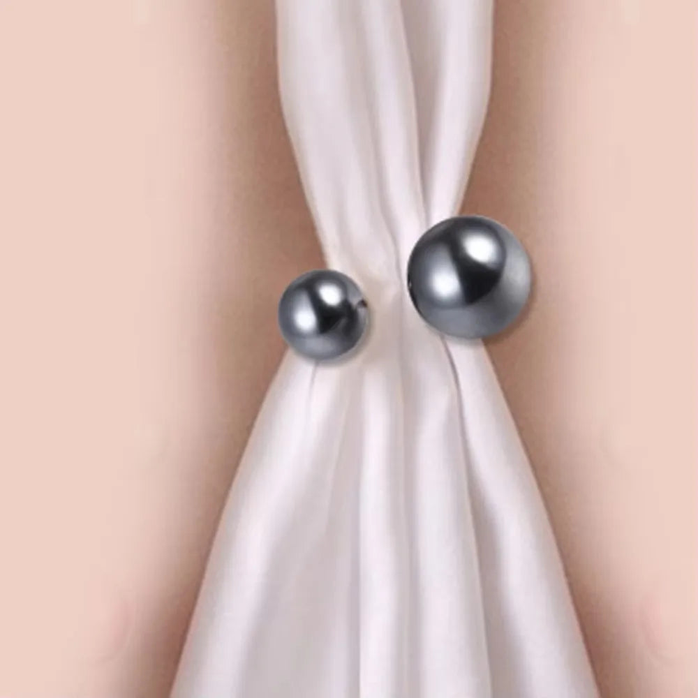 A pearl brooch jewelry set featuring two silver-toned spherical pins tied in a white silk ribbon.