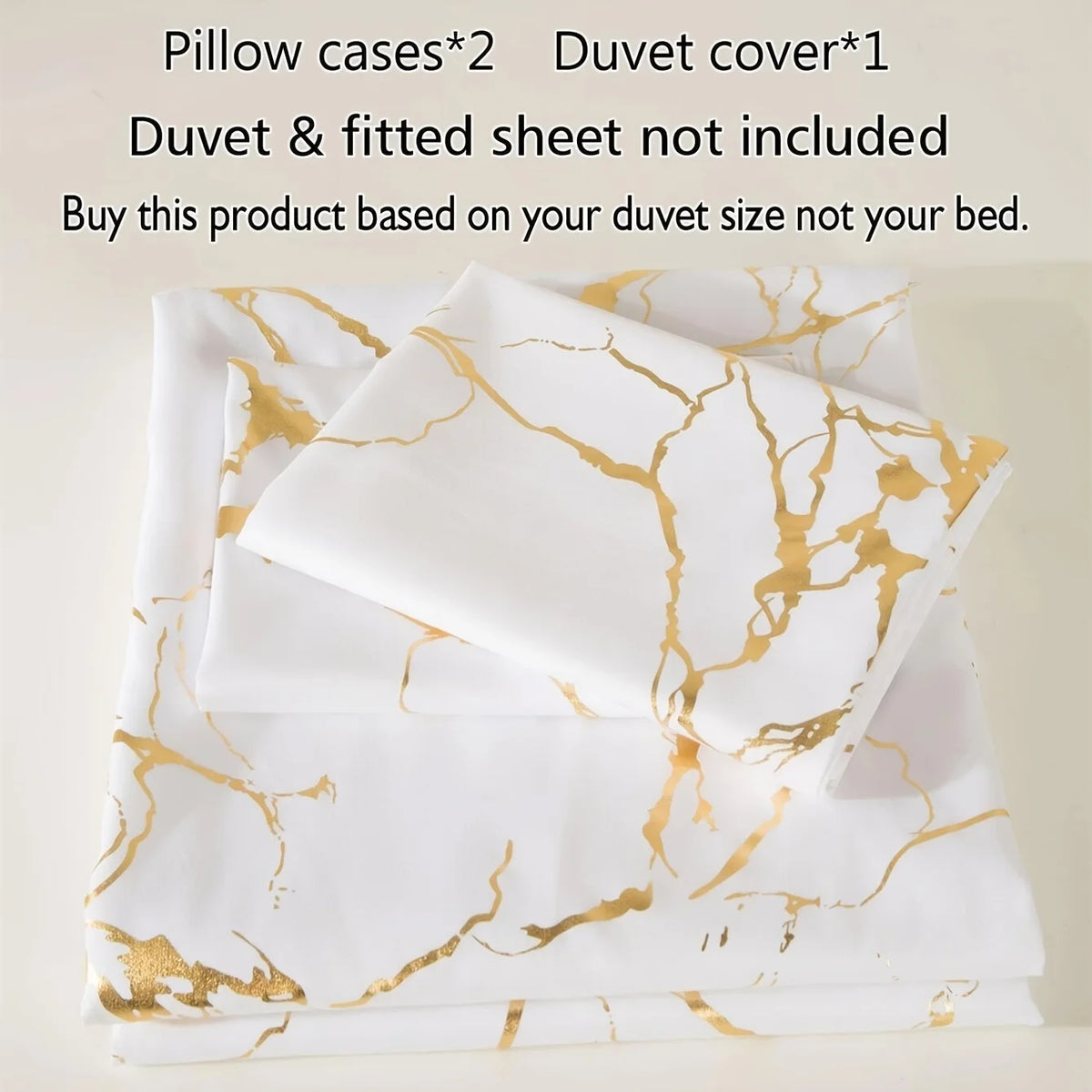 White duvet cover and pillow cases with gold marble print design stacked neatly.