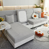 A modern gray Jacquard sofa slipcover with white accents and orange pillows on a light gray floor.