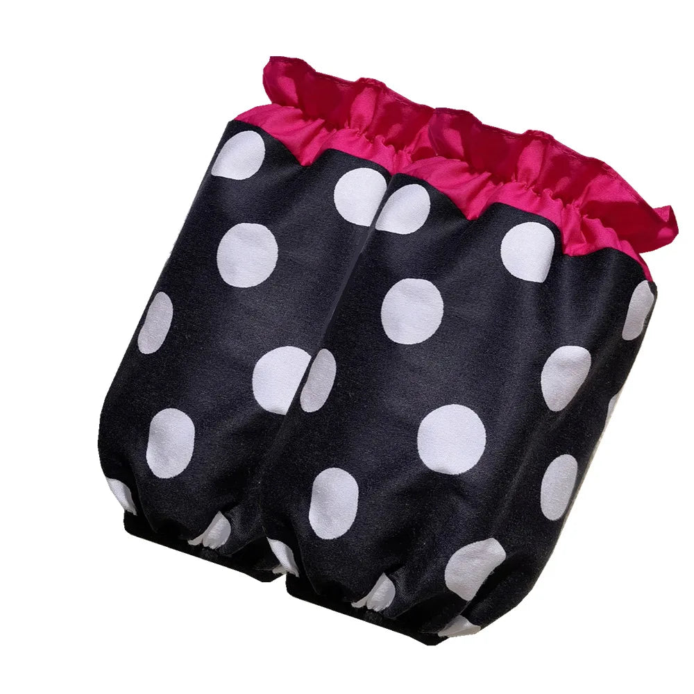 A black polka dot ruffle apron with pink trim and pockets.