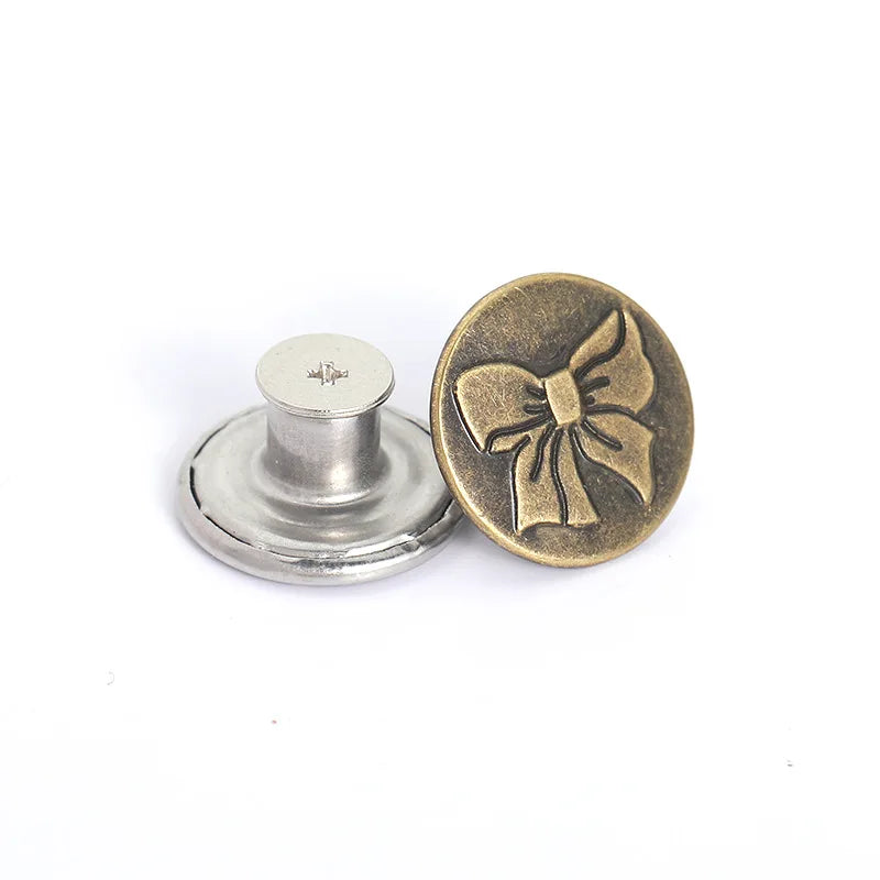 A round brass button with a bow design and a silver button shank.