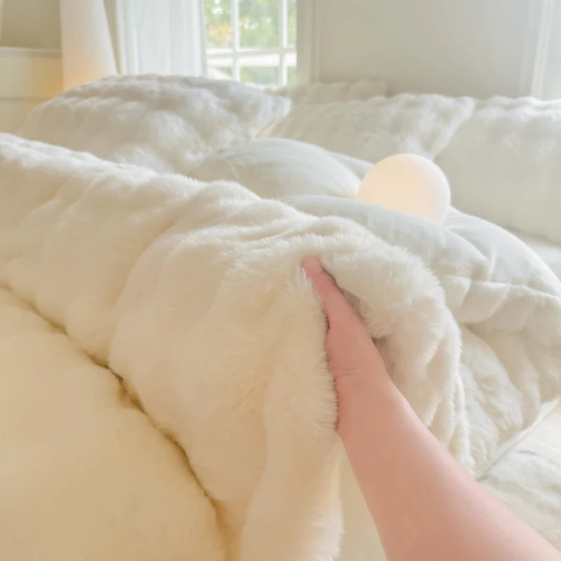 A hand is touching a fluffy white rabbit fleece duvet cover on a bed.
