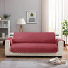 A pink quilted reversible sofa slipcover displayed in a modern living room setting.