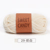 A ball of natural cream colored sweet candy yarns with a brown label and a white swatch.